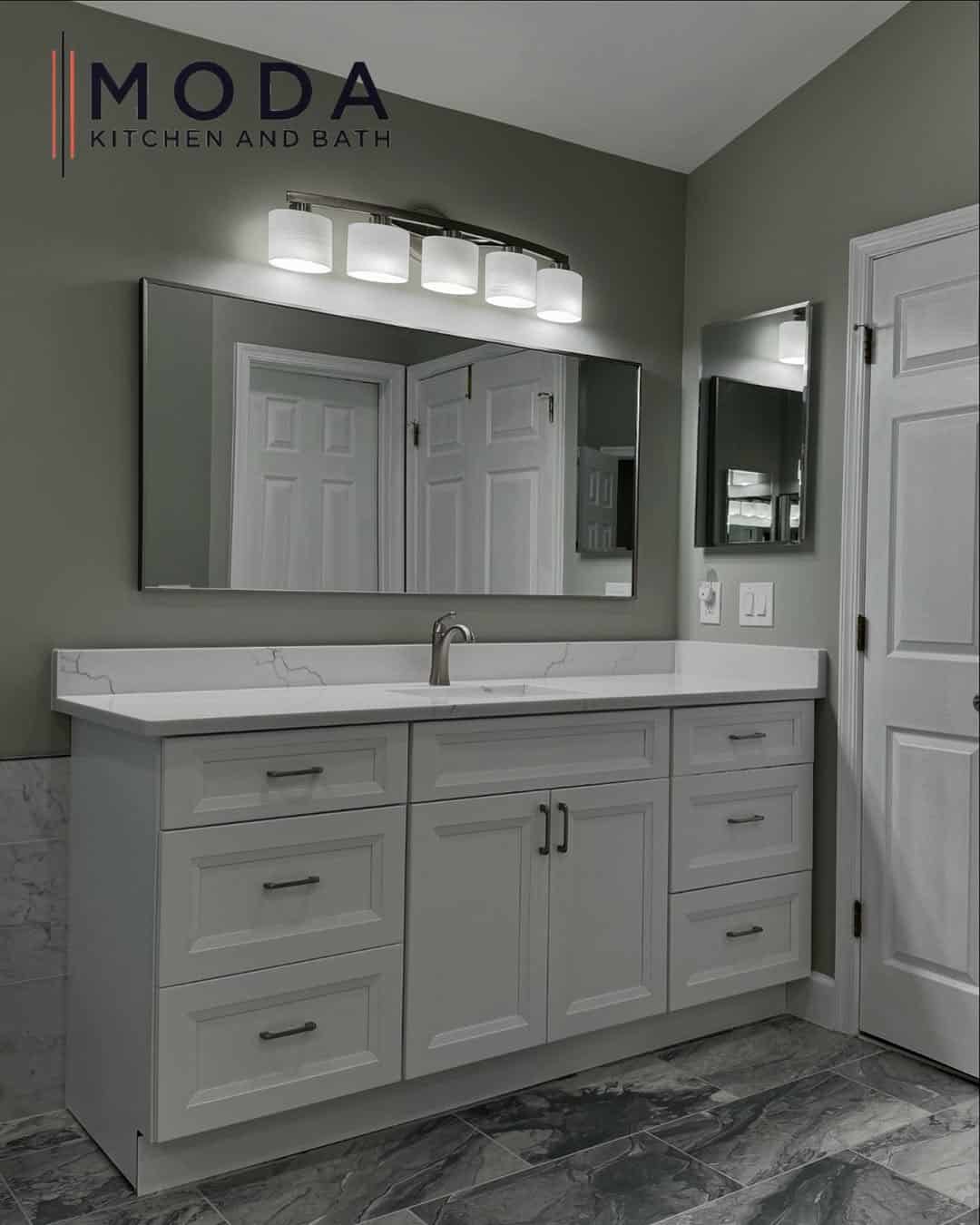Wide white shaker bathroom vanity with veined quartz countertop, brushed nickel fixtures, four-light bar, and frameless rectangular mirror