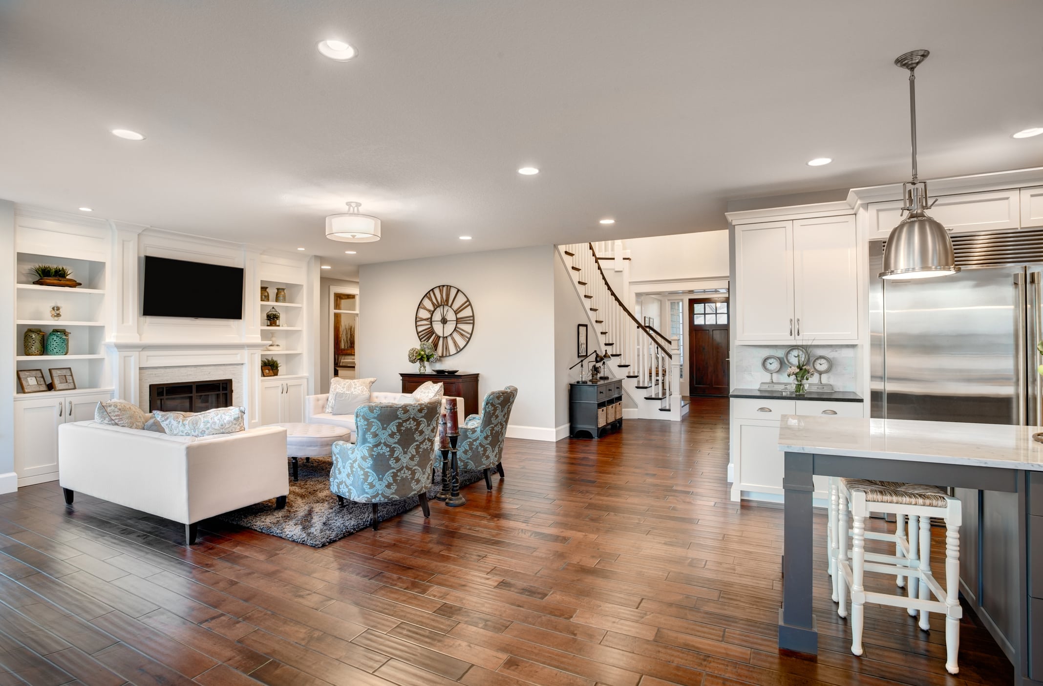 Full house remodel with open floor plan, hardwood floors, built-in shelving, fireplace, white kitchen island, and curved staircase in Northern Virginia home